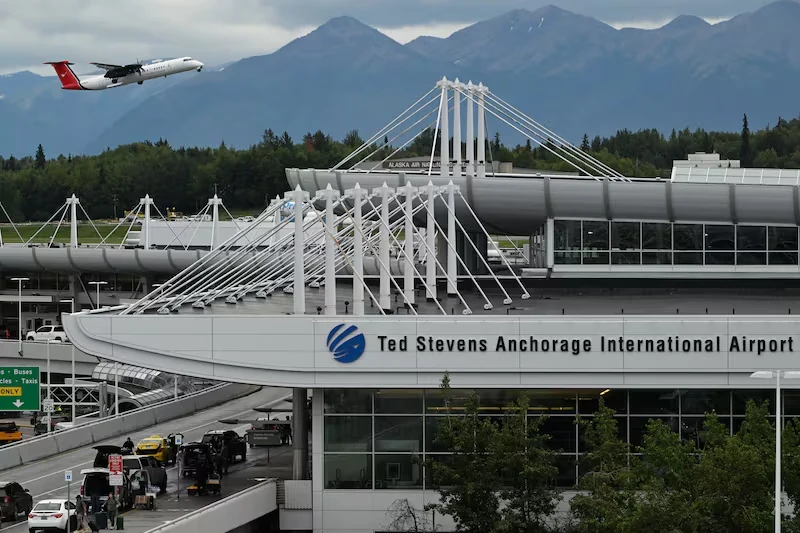 Ted Stevens Anchorage International Airport terminal with an aircraft and mountains behind